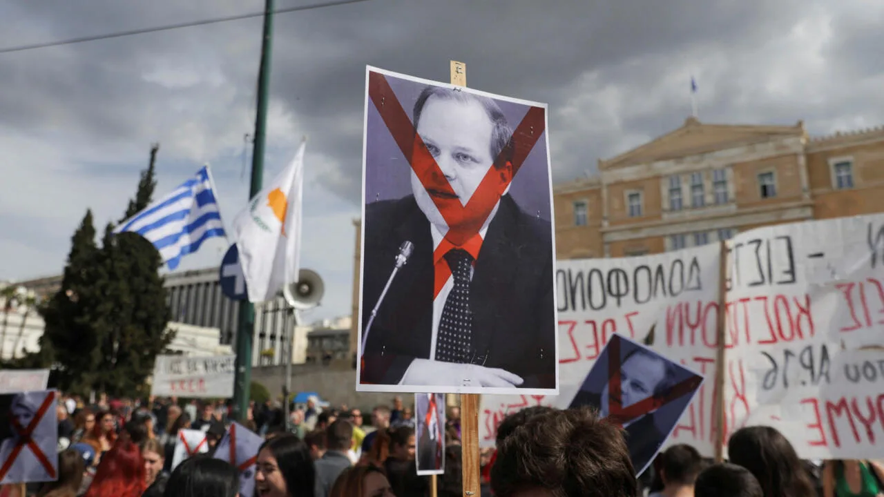 Grecia como laboratorio de ajuste económico | Ornitorrinco Atenas,marzo de 2023. Los manifestantes protestan ante el Parlamento griego. La pancarta muestra al ex ministro de Transporte griego con la cara tachada. Foto: Reuters/Louiza Vradi